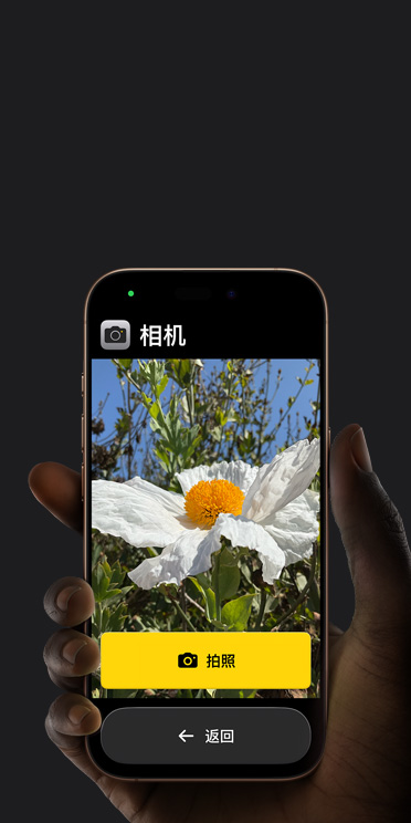 iPhone 16 Pro 屏幕显示精简的相机 app 界面，包括取景画面中的粉色花朵、“拍照”按钮及其下方的“返回”按钮。