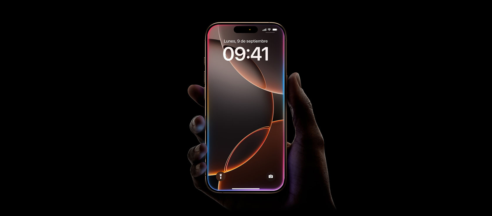 Una mano sostiene un iPhone 16 Pro en acabado titanio del desierto, diseño todo pantalla, Dynamic Island en el centro de la parte superior, esquinas redondeadas