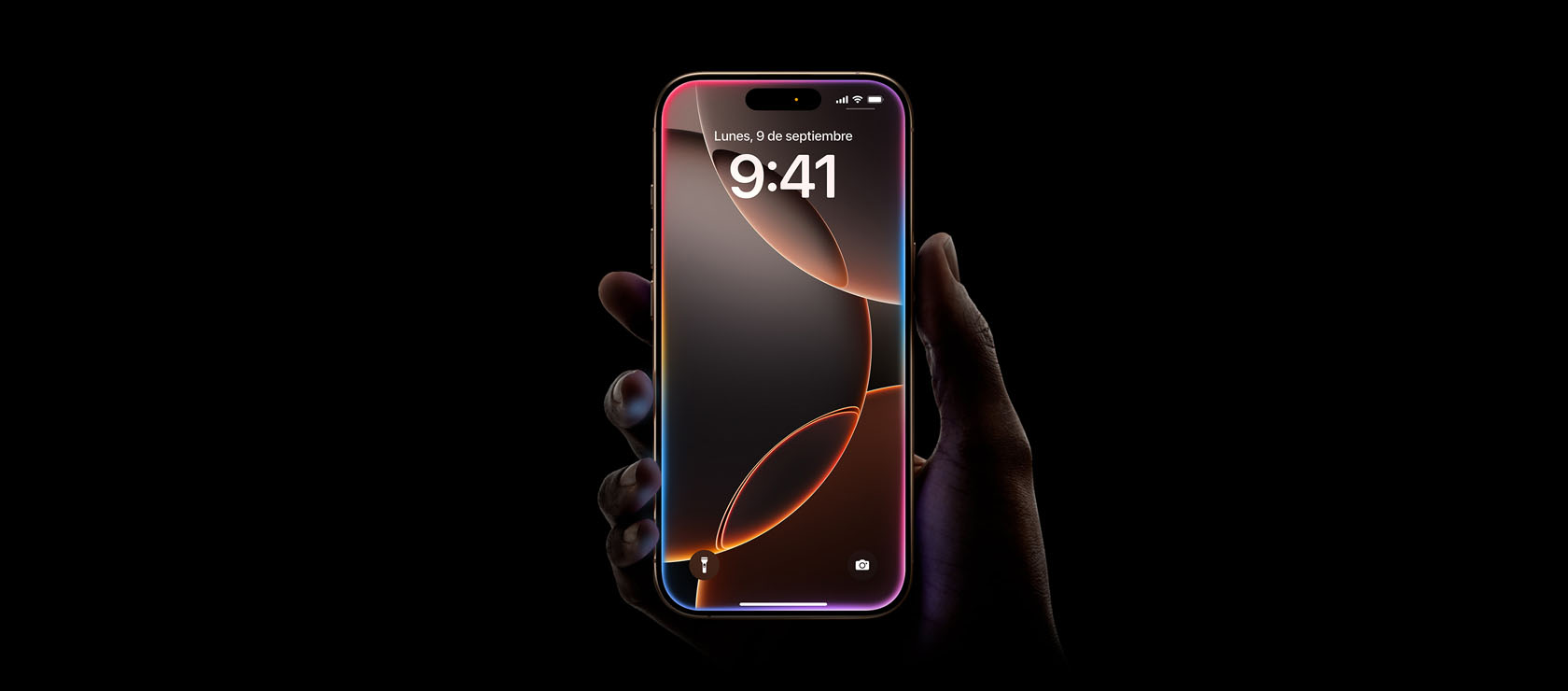 Una mano sostiene un iPhone 16 Pro en acabado titanio del desierto, diseño todo pantalla, Dynamic Island en el centro de la parte superior, esquinas redondeadas
