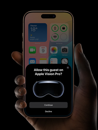 一隻手正拿著 iPhone。iPhone 螢幕上有一個視窗，當中顯示「要在 Apple Vision Pro 允許此訪客嗎？」訊息，底下是分別標示「繼續」和「拒絕」的按鈕。