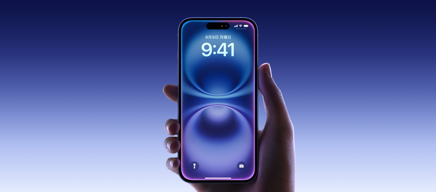 ウルトラマリンのiPhone 16を手で持っている。オールスクリーンディスプレイの最上部付近の中央にDynamic Islandがあり、ディスプレイの四隅は丸みを帯びている