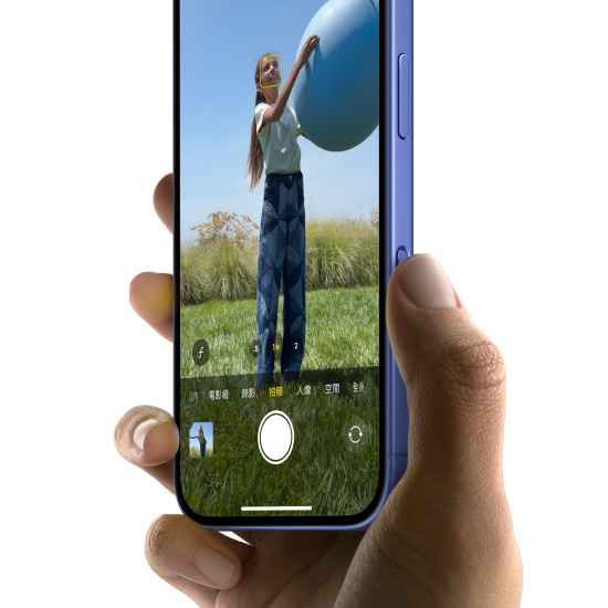 一隻手握著湛海藍色 iPhone 16，拇指在相機控制按鈕上滑動，選擇拍照功能