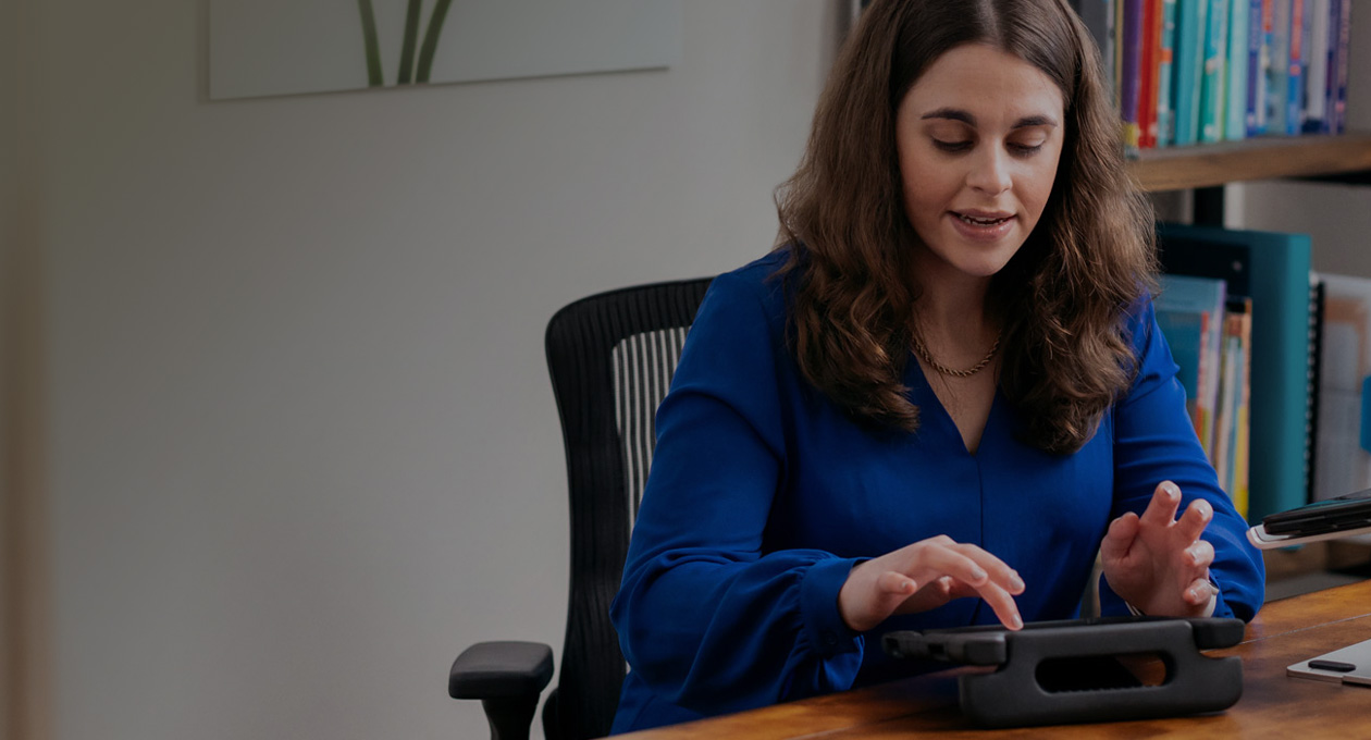 Foto van Jordyn Zimmerman, Apple Distinguished Educator en pleitbezorger voor mensen met een beperking, zittend aan een bureau en typend op een iPad-scherm