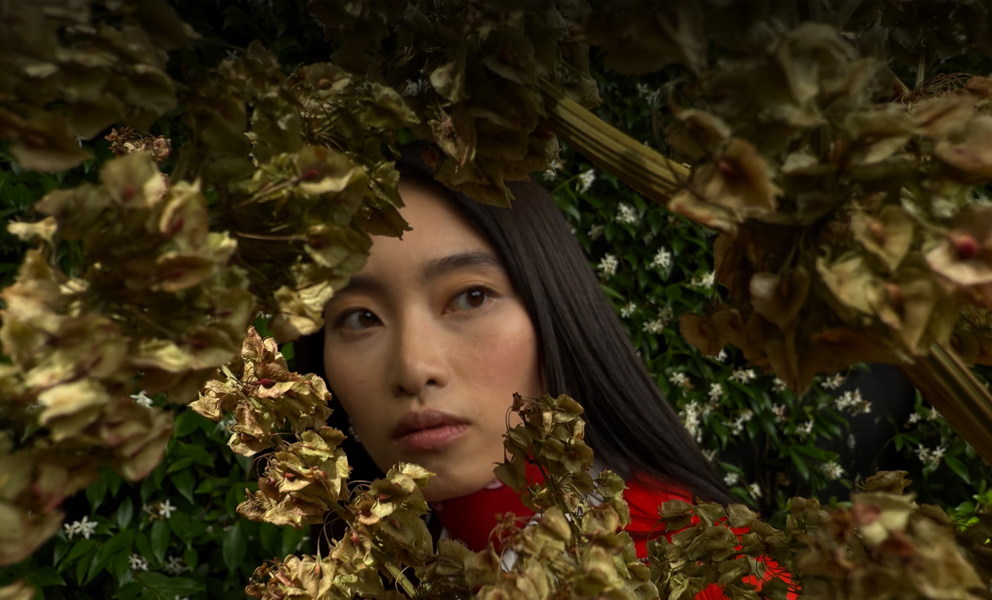 一位女士的相片特寫，相片中她被綠葉圍繞
