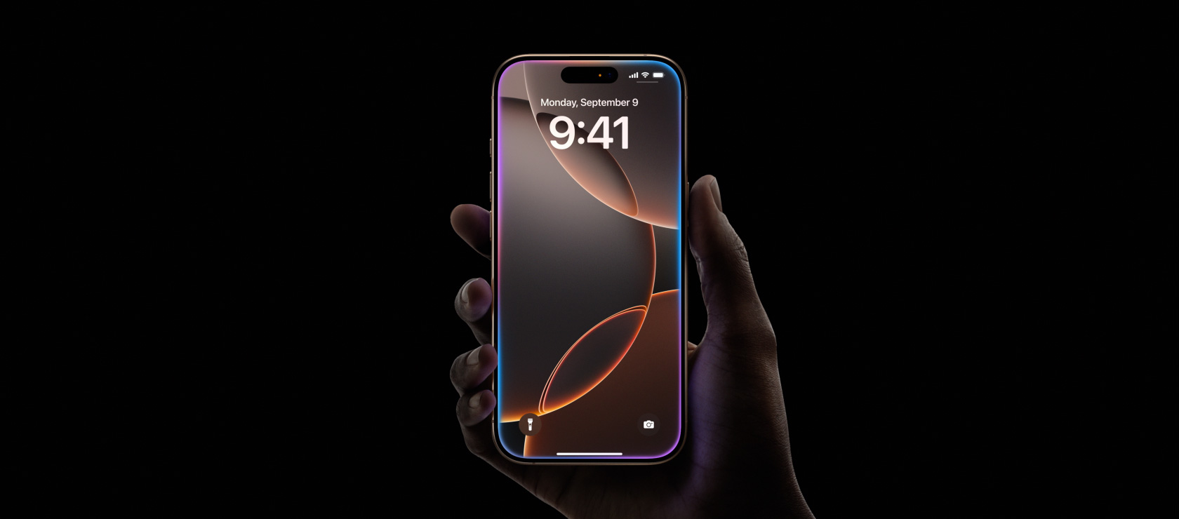 一隻手握著沙漠色鈦金屬 iPhone 16 Pro，展示全螢幕設計、近頂部中間位置的動態島，以及圓角設計