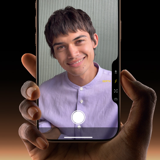 一隻手握著沙漠色鈦金屬 iPhone 16 Pro，拇指在相機控制按鈕上滑動以調整景深