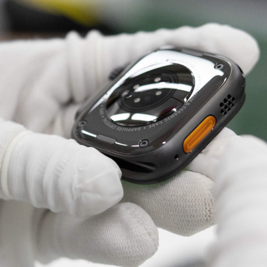 戴有手套的一雙手拿著 Apple Watch，錶底朝上
