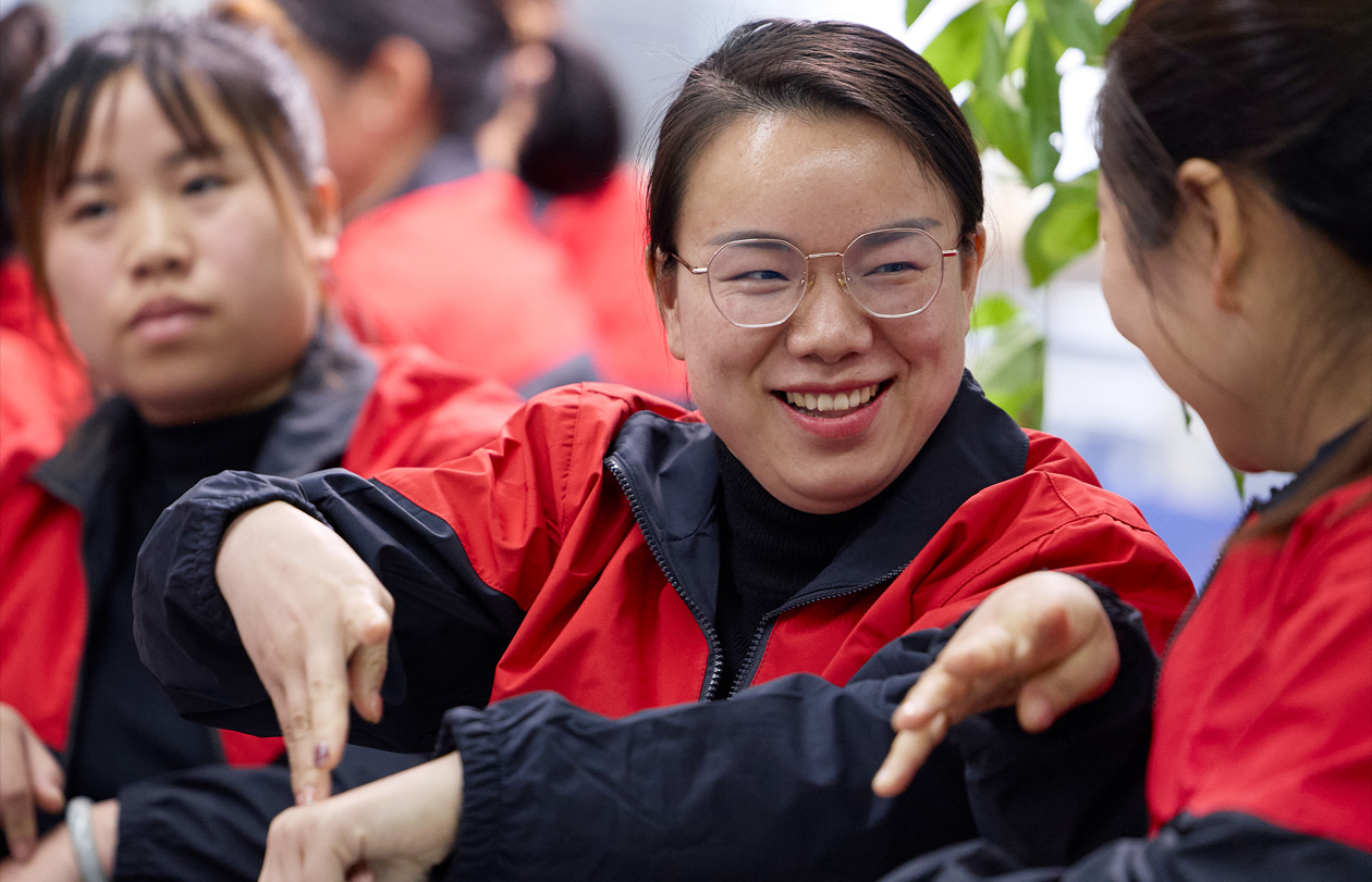 三位員工坐在一起，其中一位向另一位打手語