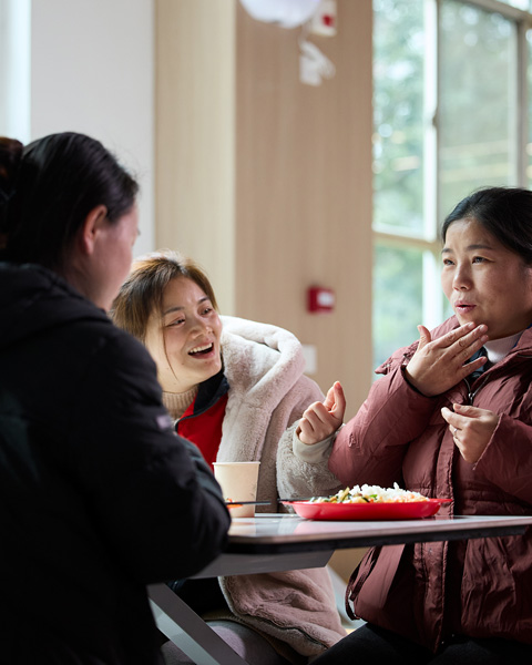 三個人坐在餐廳的桌子旁，彼此用手語溝通