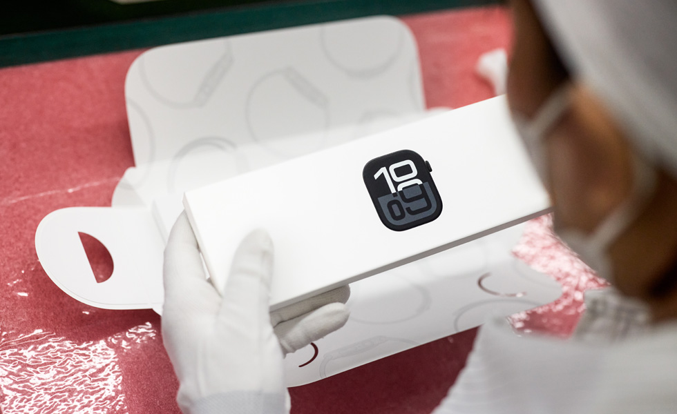 以俯視角度展示一位戴著口罩的員工包裝 Apple Watch